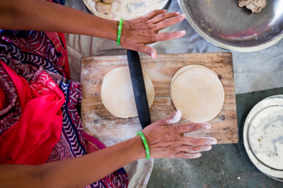 Hands using rolling pin to make the atta flour dough into Indian bread